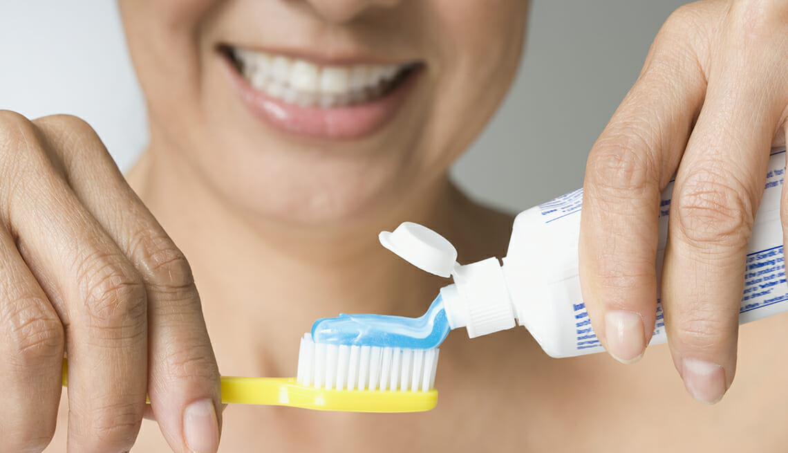 hispanic woman putting toothpaste on toothbrush
