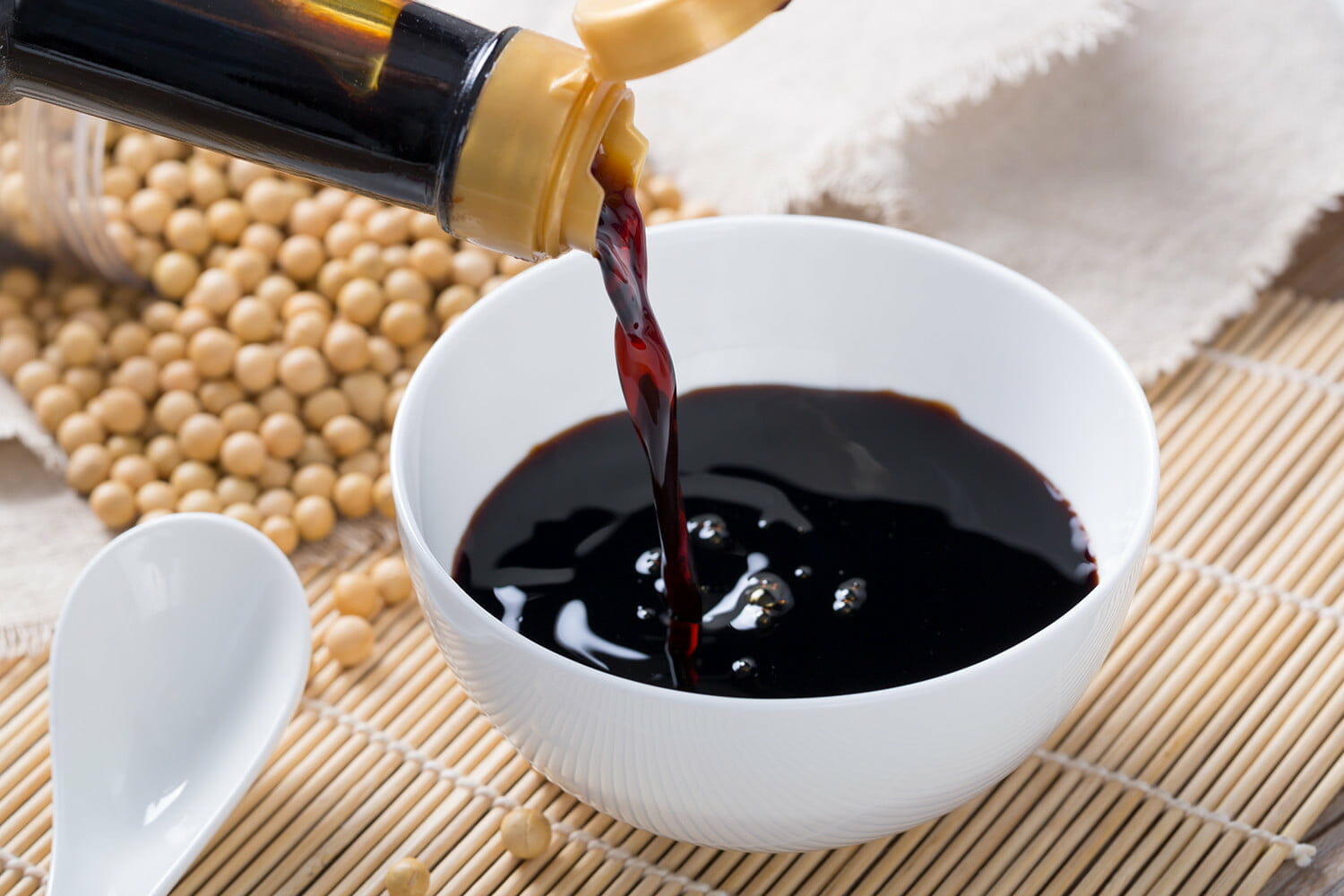 pouring soy sauce into a white bowl